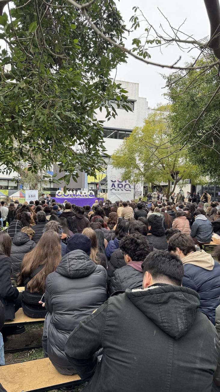 Cientos de estudiantes sentadxs en el parque de la FAU frente al escenario del CONARQ 2026